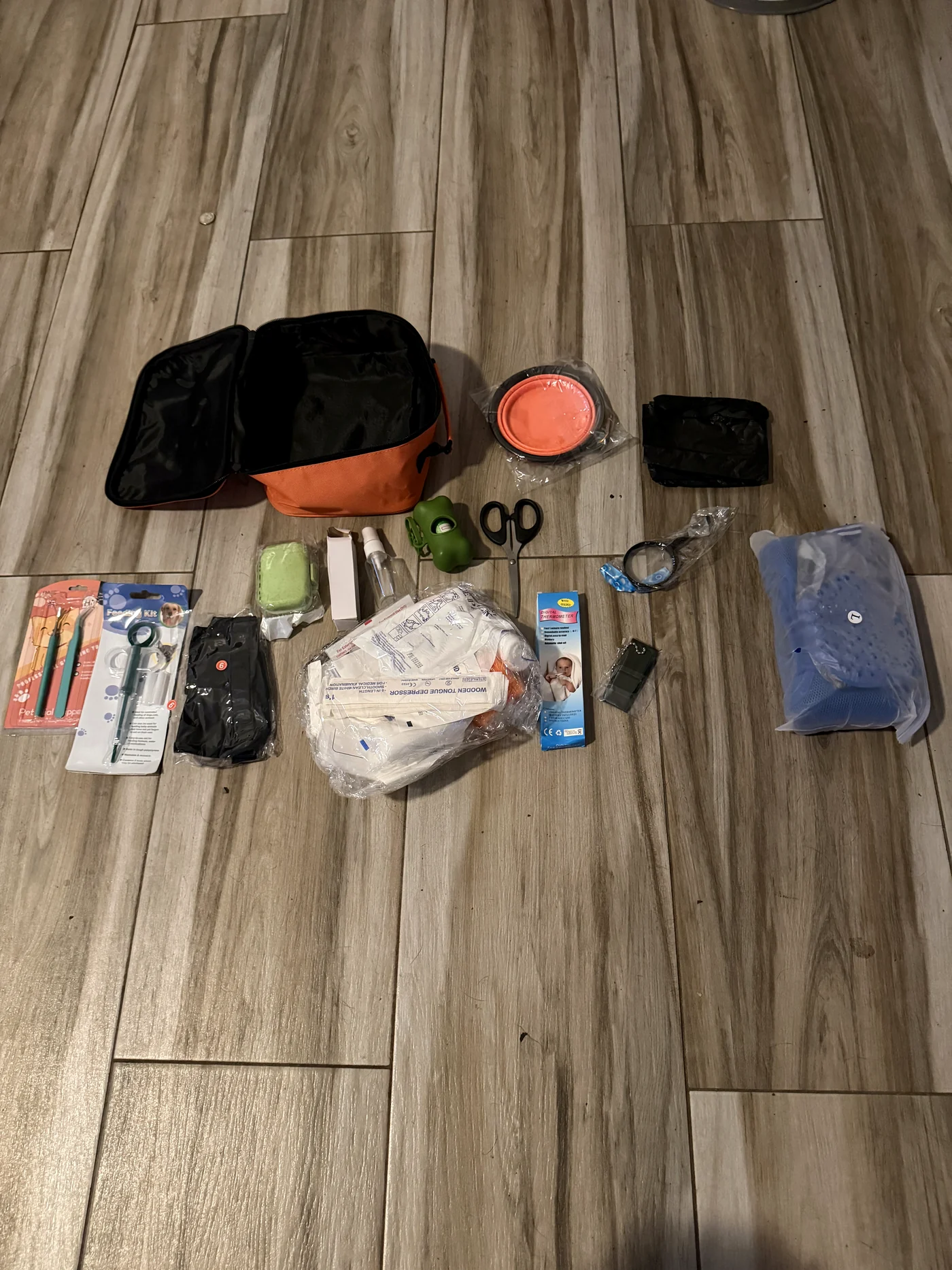 Full canine first-aid kit contents laid out - wound care, thermometer, muzzle, collapsible bowl and more